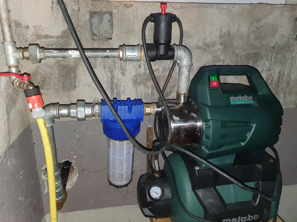 A house water system mounted in a basement with two pipes connected.